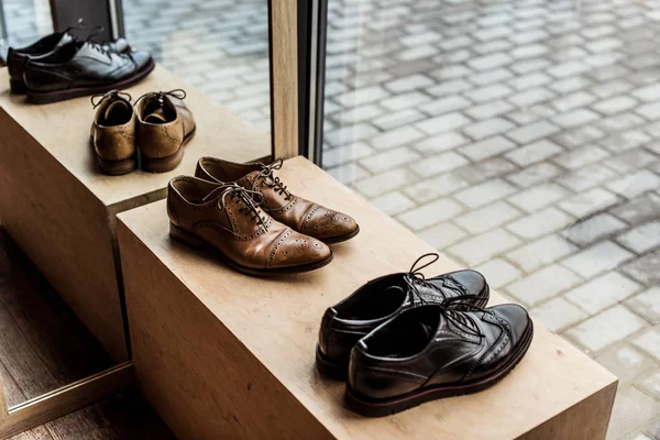 Zapatos masculinos marrones y negros modernos en escaparate en tienda - foto de stock