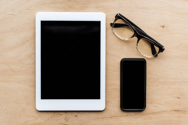Vista superior de la tableta, gafas y teléfono inteligente en la superficie de madera — Stock Photo
