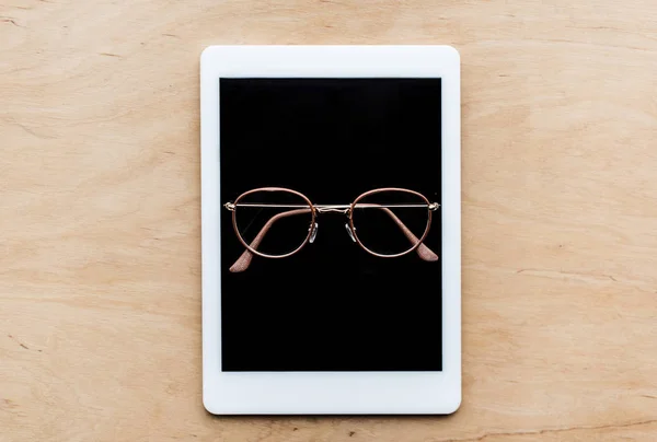 Вид зверху окуляри на планшеті на дерев'яному столі — стокове фото