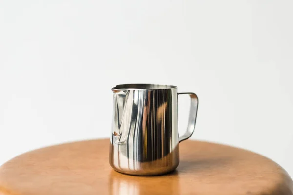 Stainless milk pitcher on wooden chair isolated on white — Stock Photo