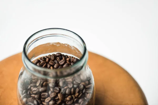 Vista de ángulo alto de botella de vidrio con granos de café en la mesa aislado en blanco - foto de stock