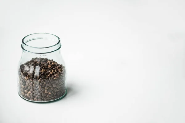 Botella de vidrio con granos de café en blanco - foto de stock