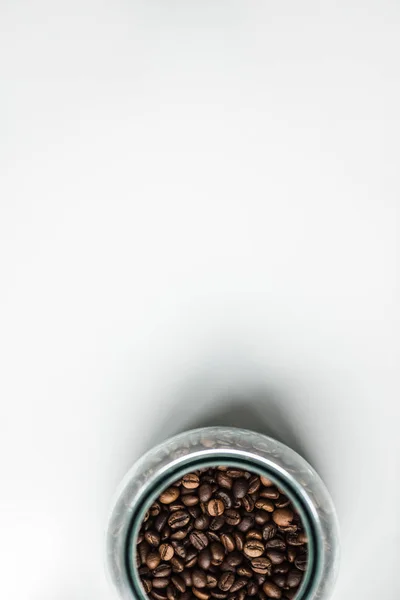 Vista superior da garrafa de vidro com grãos de café em branco — Fotografia de Stock