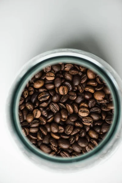 Vista superior de la botella de vidrio con granos de café en blanco - foto de stock