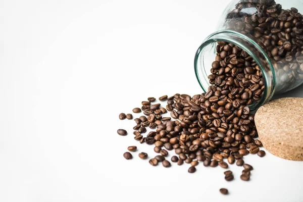 Verstreute Kaffeebohnen aus Glasflasche und Kork isoliert auf weiß — Stockfoto