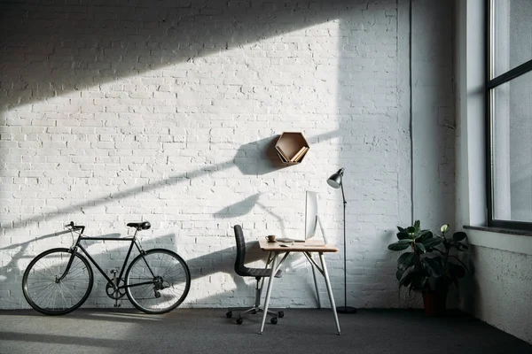 Vélo et table de travail avec ordinateur dans le bureau — Photo de stock