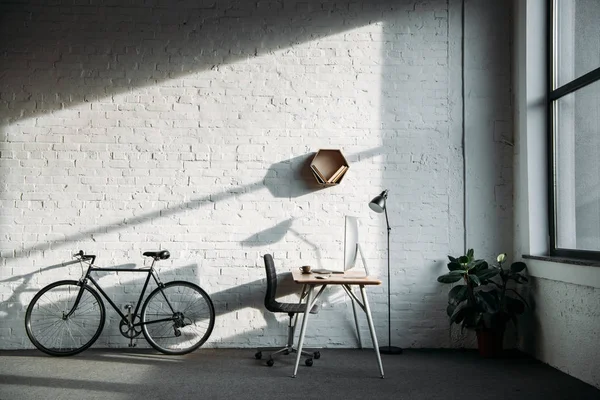 Bicycle and working table with computer in office — Stock Photo