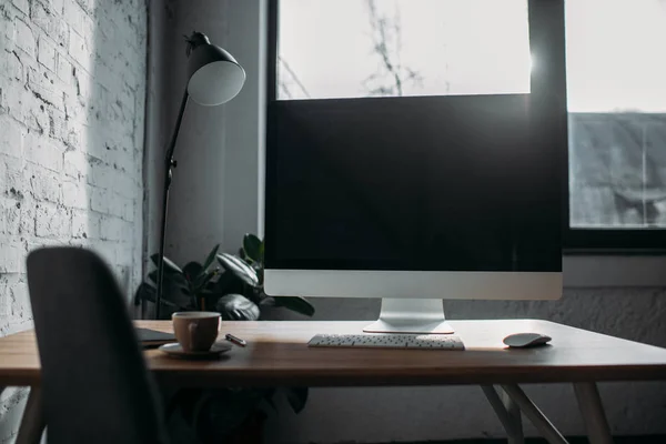 Computer, table lamp and cup in office — Stock Photo