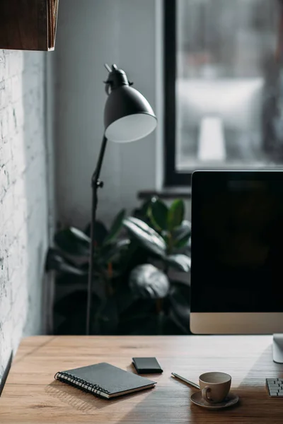 Notizbuch mit Tasse und Tischlampe auf dem Bürotisch — Stockfoto