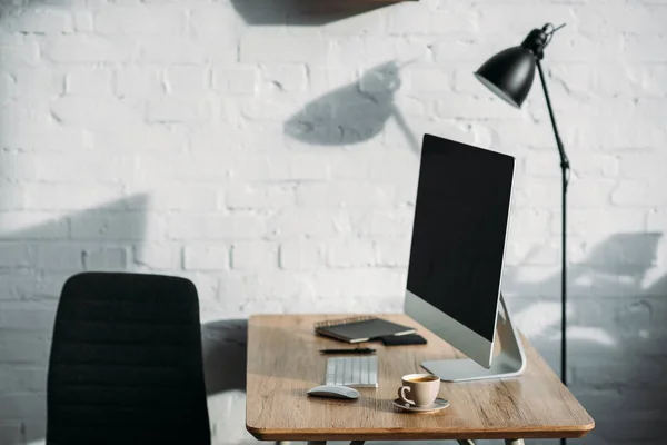 Computador e copo na mesa de madeira no escritório — Fotografia de Stock