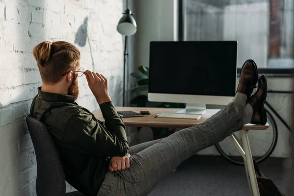 Vista lateral del hombre de negocios sentado con las piernas en la mesa de la oficina - foto de stock