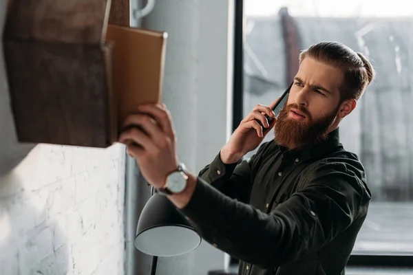 Uomo d'affari che parla con lo smartphone e guarda il libro sullo scaffale — Foto stock