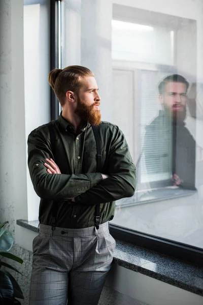 Guapo hombre de negocios barbudo con los brazos cruzados mirando hacia otro lado - foto de stock