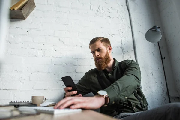 Bel homme d'affaires barbu regardant smartphone dans le bureau — Photo de stock