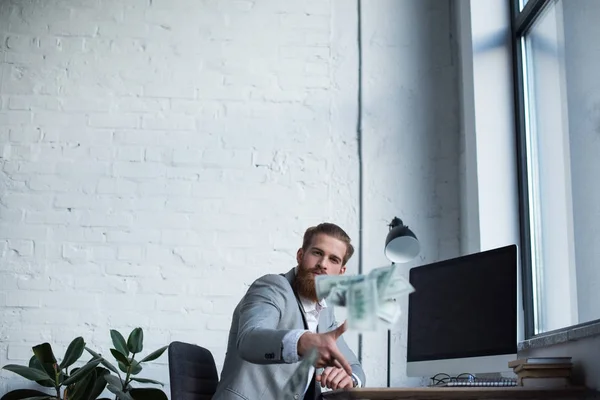 Handsome businessman throwing dollars in office — Stock Photo