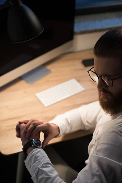 Geschäftsmann schaut abends auf Uhr im Büro — Stockfoto