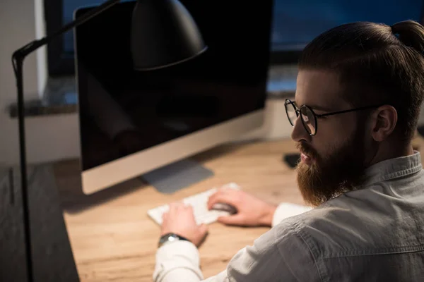 Hombre de negocios escribiendo algo en el teclado en la oficina y mirando hacia otro lado - foto de stock