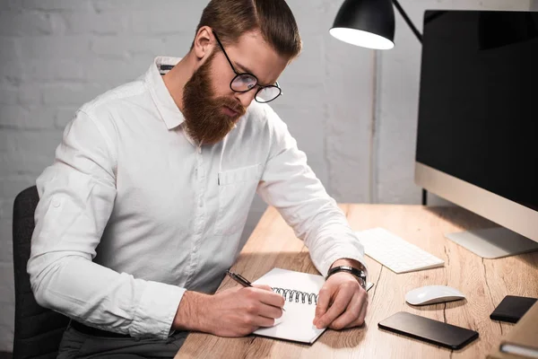 Hombre de negocios escribiendo algo a cuaderno en la oficina - foto de stock