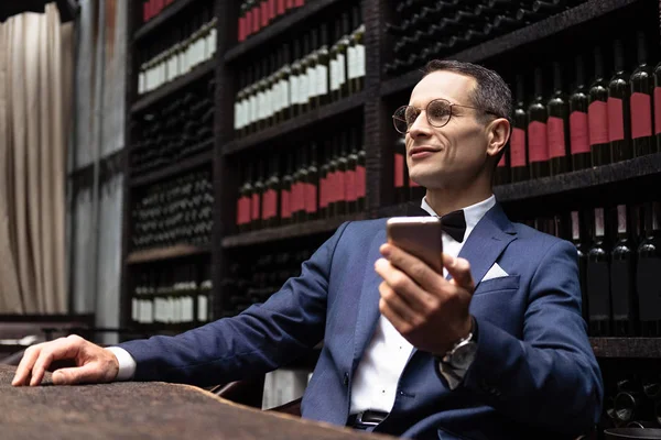 Homem bonito em terno elegante usando smartphone no restaurante — Fotografia de Stock