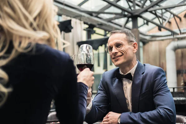 Feliz pareja de adultos tintineo vasos de vino en el restaurante - foto de stock