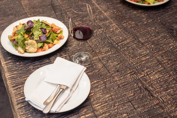 Savoureuse salade avec vin sur table rustique en bois — Photo de stock