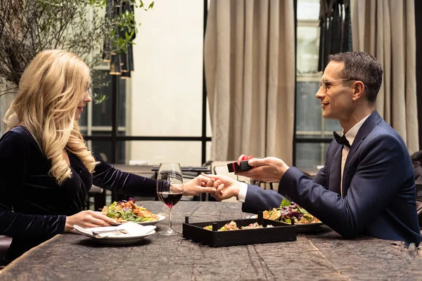 Seitenansicht eines Mannes, der Freundin Valentinstag-Geschenk im Restaurant überreicht — Stockfoto