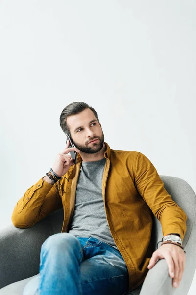 Hombre guapo hablando por teléfono inteligente y mirando hacia otro lado aislado en blanco - foto de stock