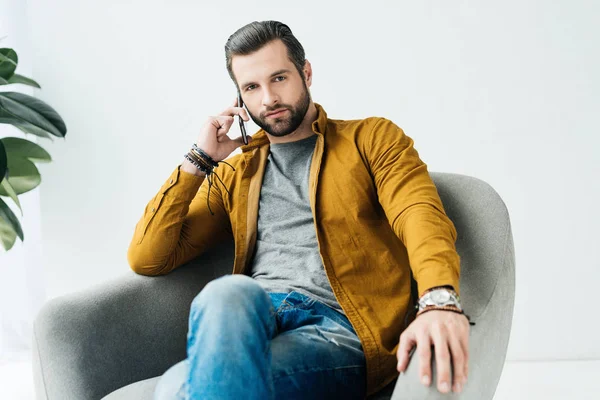 Hombre guapo hablando por teléfono inteligente y mirando a la cámara - foto de stock