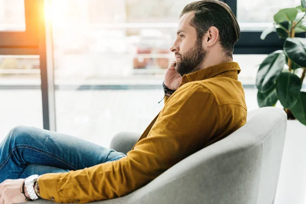 Vista lateral del hombre guapo hablando por teléfono inteligente - foto de stock