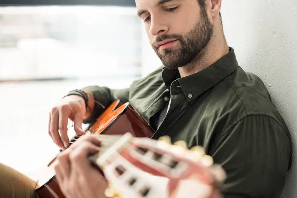 Guapo músico tocando la guitarra acústica - foto de stock