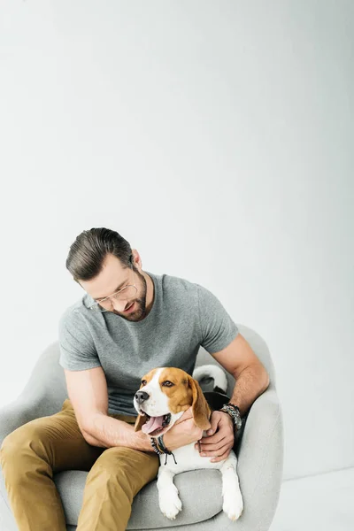 Man hugging yawning dog and sitting on armchair — Stock Photo