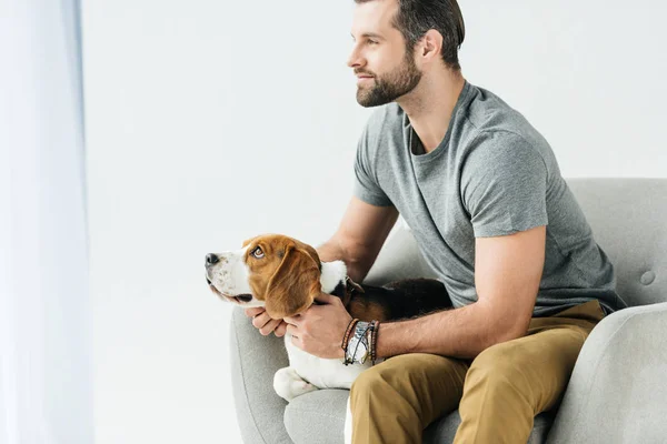 Vista lateral del hombre guapo sentado en sillón con perro - foto de stock