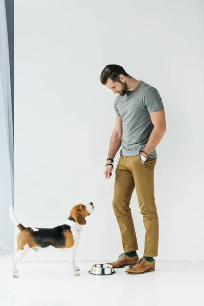 Чоловік стоїть біля миски для домашніх тварин і дивиться на собаку — стокове фото