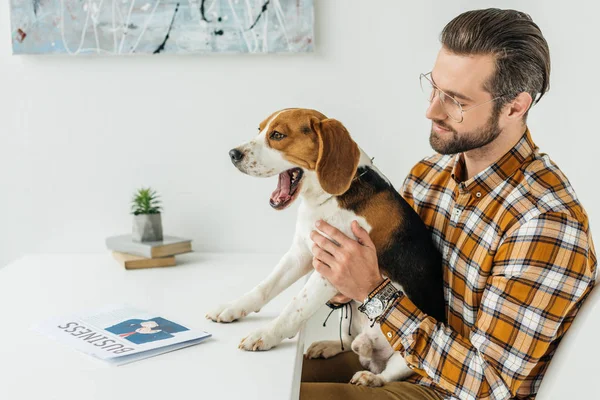 Hombre de negocios sosteniendo perro bostezo en la mesa - foto de stock