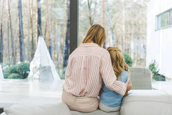 Rückansicht der Mutter, die ihre kleine Tochter zu Hause umarmt — Stockfoto