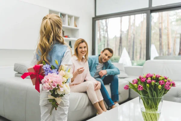 Selective focus of little daughter with presents for mathers day and parents on sofa at home — Stock Photo