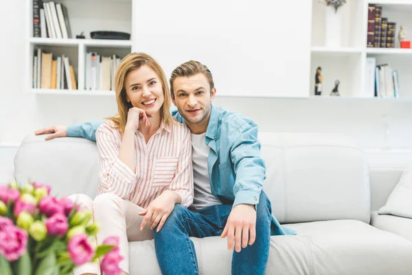 Ritratto di una coppia sorridente appoggiata sul divano di casa — Foto stock