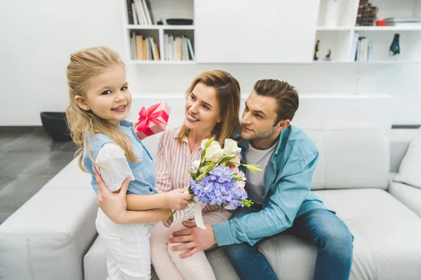 Side view of daughter greeting smiling mother with mothers day at home — Stock Photo