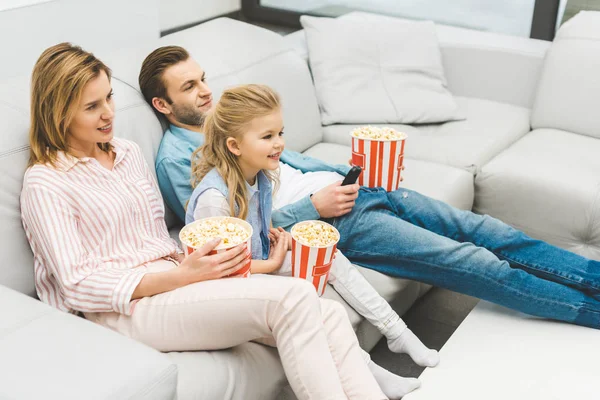 Усміхнена сім'я з попкорном дивитися фільм разом вдома — стокове фото