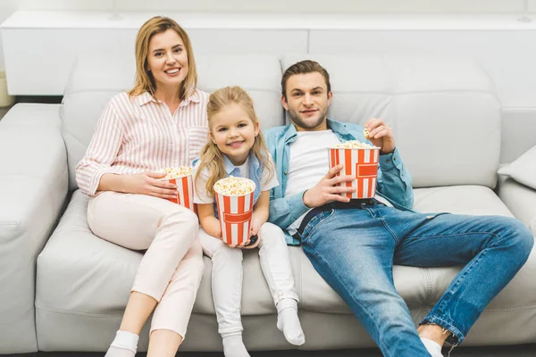Усміхнена сім'я з попкорном дивитися фільм разом вдома — стокове фото