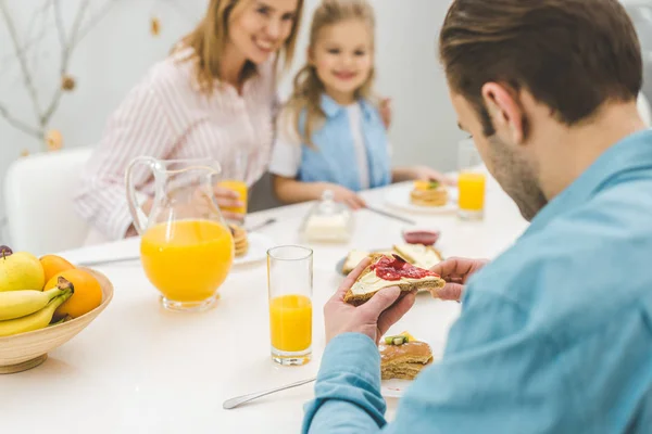 Enfoque selectivo del hombre desayunando junto con la familia en casa - foto de stock