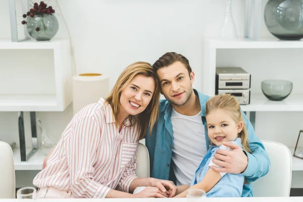 Portrait of smiling parents and daughter looking at camera at home — Stock Photo