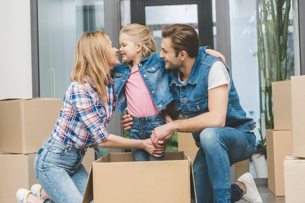 Retrato de pais sorridentes e filhinha em caixa de papelão na nova casa, movendo-se para casa conceito — Fotografia de Stock