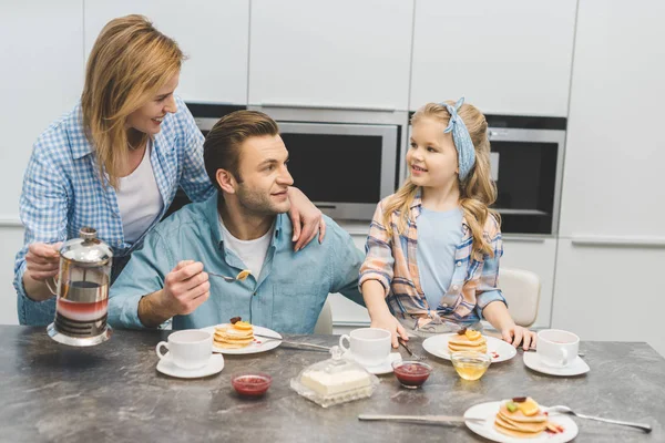 Padres e hijita desayunando juntos en casa - foto de stock