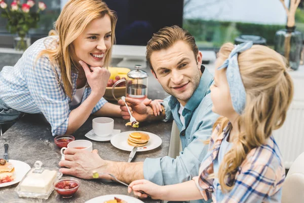 Parents et petite fille prennent le petit déjeuner ensemble à la maison — Photo de stock