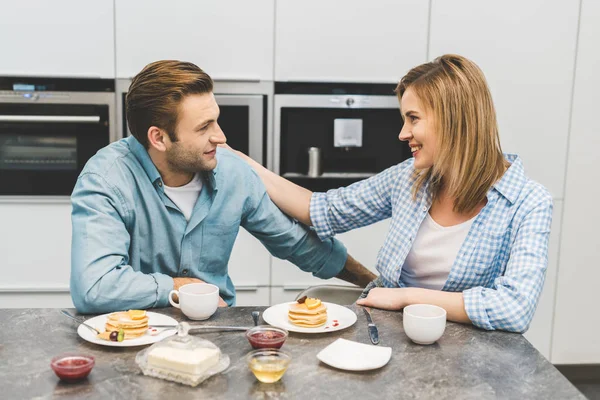 Retrato de casal olhando um para o outro durante o café da manhã em casa — Fotografia de Stock