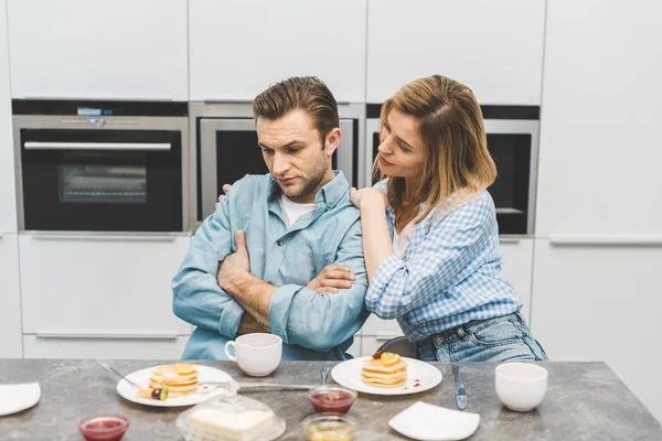 Frau umarmt verärgerten Ehemann beim Frühstück zu Hause — Stockfoto