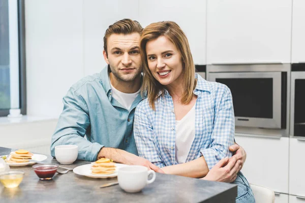 Портрет усміхненої пари, що сидить за столом зі сніданком вдома — стокове фото