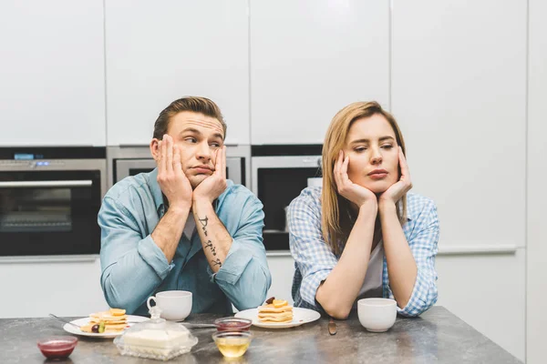 Portrait de couple argumenté assis à table avec petit déjeuner à la maison — Photo de stock