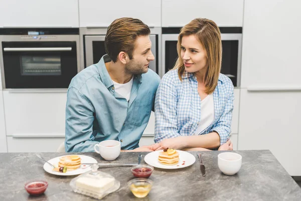 Retrato de pareja mirándose durante el desayuno en casa - foto de stock